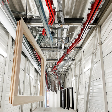 The overhead conveyor systems from CALDAN Conveyor are in operation with large metal frames in a production line environment